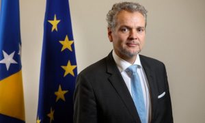 šef šef Delegacije EU u BiH Johann Sattler tamni sako bijela košulja svijetloplava kravata maramica u džepu sakoa prosijeda kosa iza njega zastave BiH i EU bijeli zid dan unutra