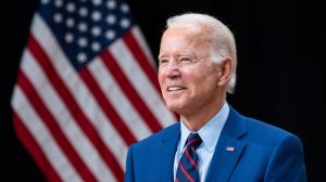 Biden ima 79 godina joe biden smije se i stoji pored američke zastave