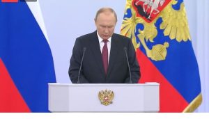 državni udar putin stoji za govornicom iza njega zastava