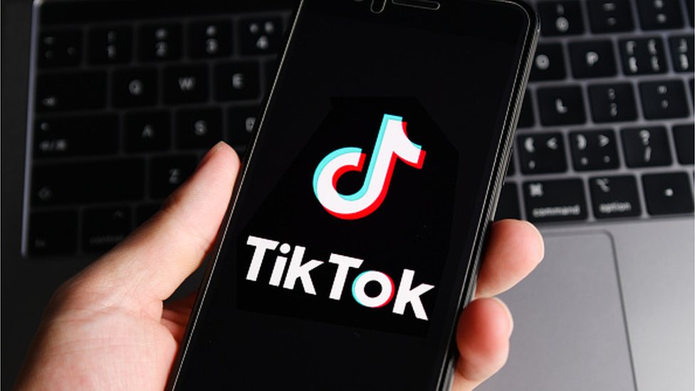 TikTok je postao globalna senzacija drži u ruci mobitel sa tiktok aplikacijom laptop