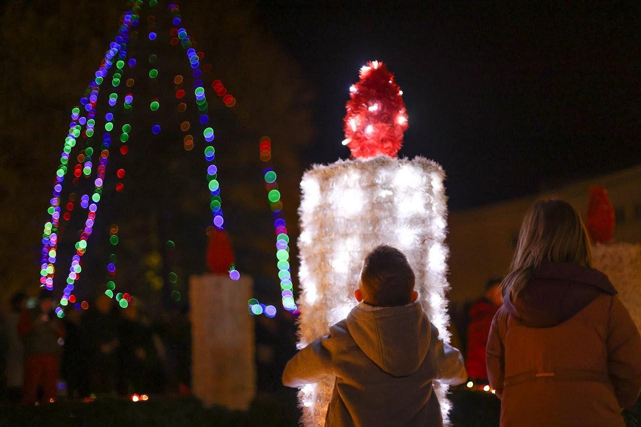 Počeo Advent u Mostaru noć dječak s majkom uslikan s leđa gleda u adventsku svijeću novogodišnji ukrasi iza Mostar