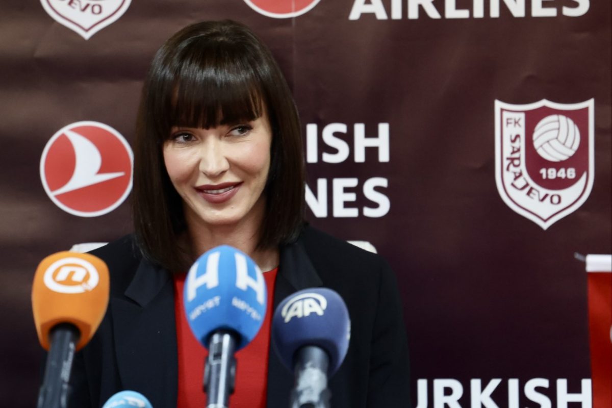 Direktorica FK Sarajevo Ajla Alimanović ošišana na bob tamno smeđa kosa smije se na konferenciji za novinare tamno plavi sako bordo majica ispred nje mikrofoni tv kuća iza natpisi FK Sarajevo i Turkish Airlines