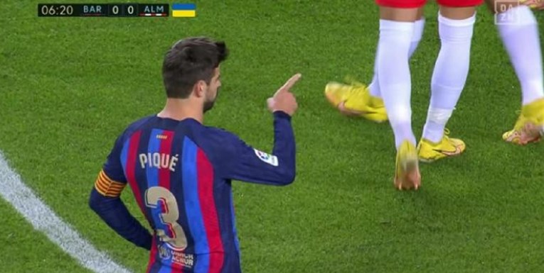 tražio da penal puca Gerard Pique pokszuje prstom na nekoga ko se ne vidi na slici u dresu barcelone na travi utakmica protiv Almerije vide se noge u bijelim štucnama i žutim kopačkama igrača koji stoje ispred njega