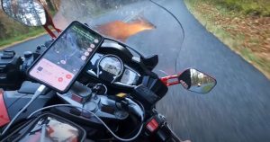 nalet motocikla na jelena motor pri vožnji lokalnim putem udara u jelena prednji dio motora kamera snima sa kacige vozača mobittel pokazuje rutu puta dan okolo šuma crna vijugava cesta retrovizori crna boja na motoru