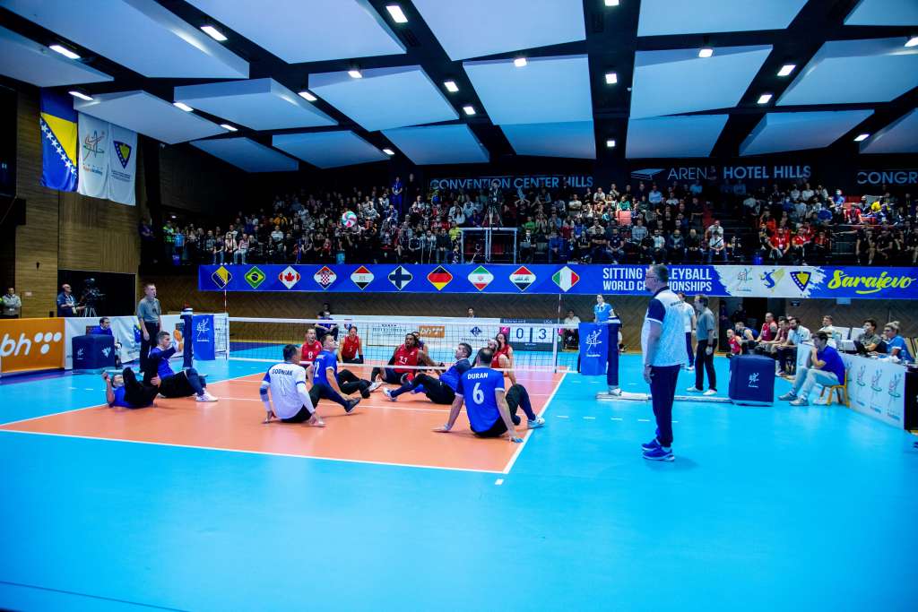 BiH porazila Japan sjedeća odbojka utakmica u dvorani lavi i crni dresovi trener stoji pored u plavoj majici i crnoj trenirci plava podloga oko terena koji je smeđe boje publika u daljini na tribinama