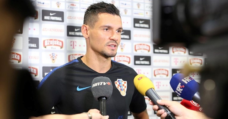 Lovren izazvao skandal Dejan Lovren pred novinarima mikrofoni crna nike majica sa grbom Hrvatske iza njega panel sa reklamama crna kosa u magli novinari