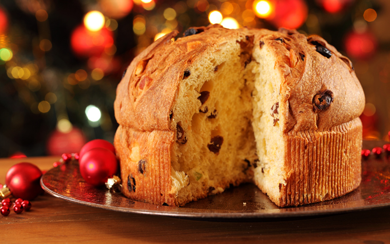 panettone na zlatnom tanjiru iza okićena jelka